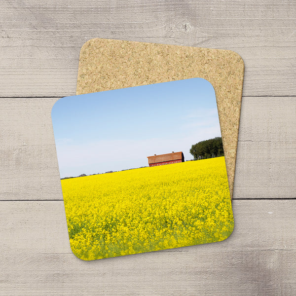 Photo coasters of a red barn sitting in a field of canola. Home accessories by Edmonton based photographer & artist, Larry Jang
