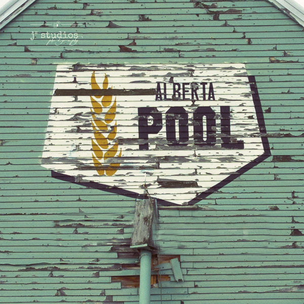 Picture of the iconic Alberta Wheat Pool logo on the side of a weathered wooden grain elevator.