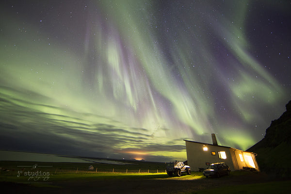 Aurora Rain is an image of the Northern Lights dancing over a house and ocean in Southern Iceland. Aurora photography.