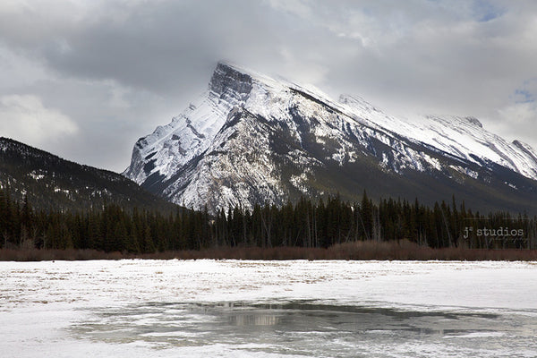 Image of Rundle Mountain in Banff National Park looming over a frozen lake. Canadian Winter Paradise.