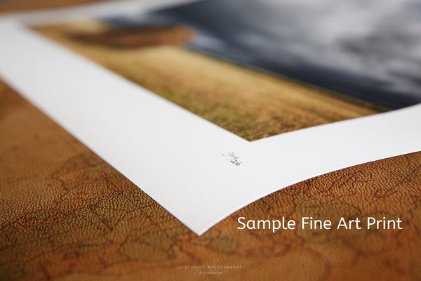 Close-up of a signed fine art paper print with a white border resting on a textured brown surface.
