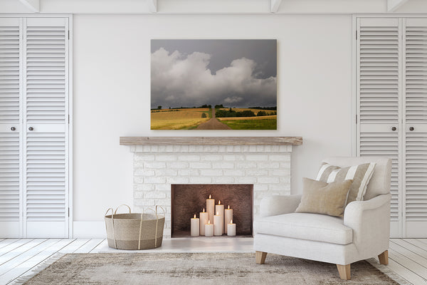 Living room decor with a fireplace. Big print of a prairie country road leading into summer rain storm.