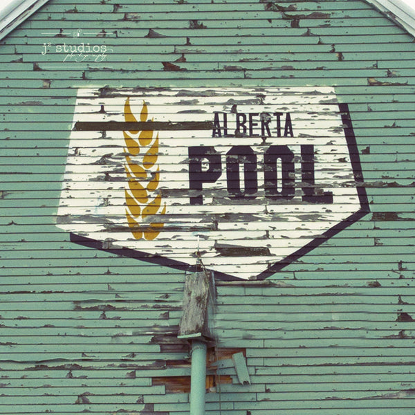 Picture of the iconic Alberta Wheat Pool logo on the side of a weathered wooden grain elevator. 
