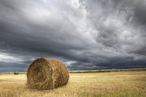 Dramatic image of a hay bale in farmer's field bracing itself for the incoming storm. 