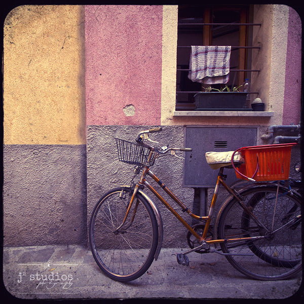 Bike Baskets in Monterosso is an art print of a parked bicycle in Cinque Terre.
