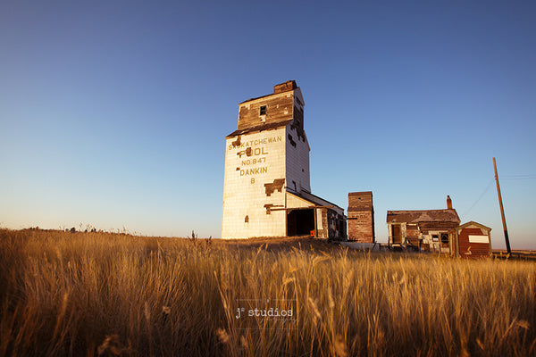 Image of two grain elevators defying the test of time and standing alone on the Saskatchewan Prairies. Heritage themed photography.