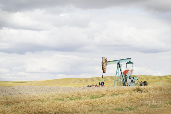 Prairie Pump is an art print of an aquamarine blue oil pump working away in this vast prairie field.