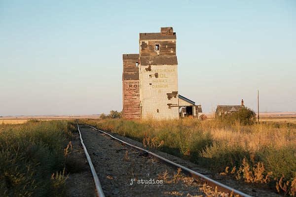 Image of a pair of grain elevators standing steadfast along the Saskatchewan railroad tracks. Prairies Photography.